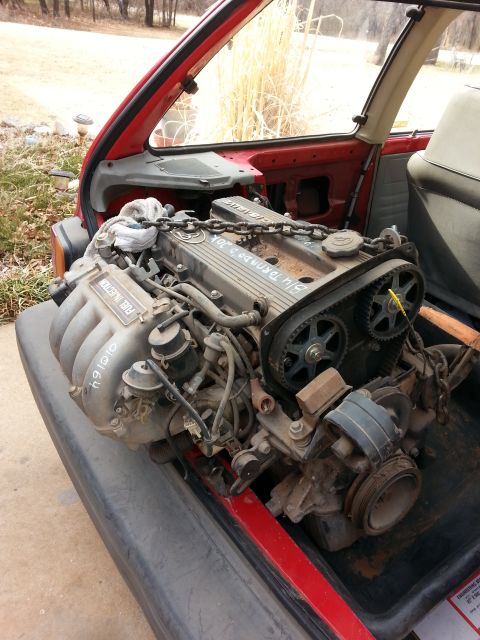 1991 Ford Festiva - Engine with 'FUEL INJECTION' text visible, is placed inside the interior of a red vehicle.