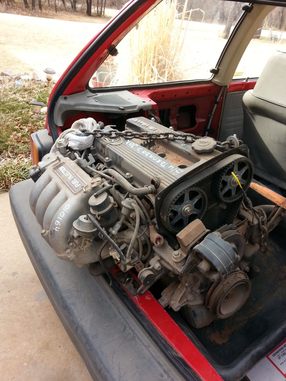 Engine with 'FUEL INJECTION' visible, inside a red car