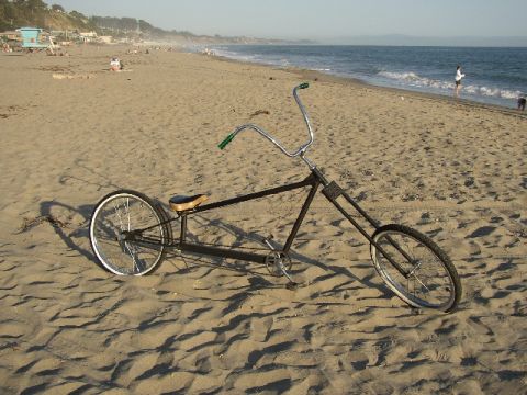 1989 Ford Bronco - Chopper bicycle parked on the sand near the ocean waves.