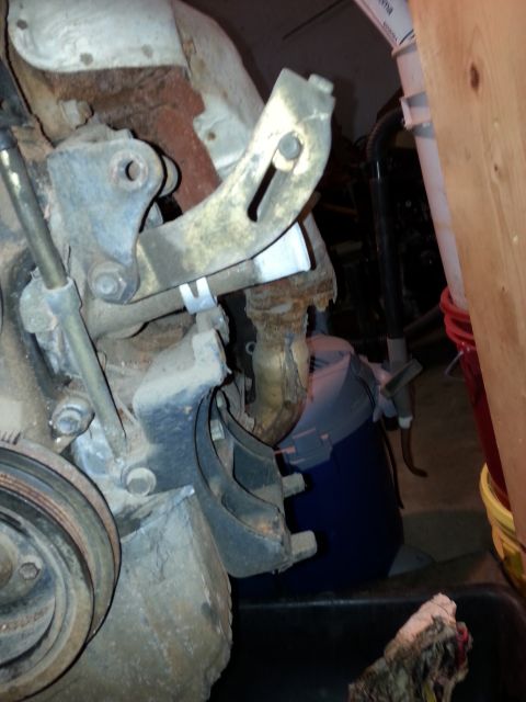 1991 Ford Festiva - A close-up view of a rusty engine component, possibly a bracket or mount, with a pulley visible.