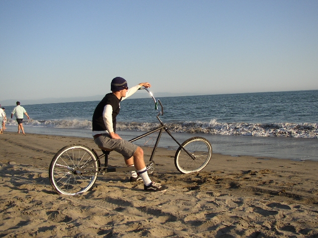 Man riding custom chopper bicycle on a beach by the ocean
