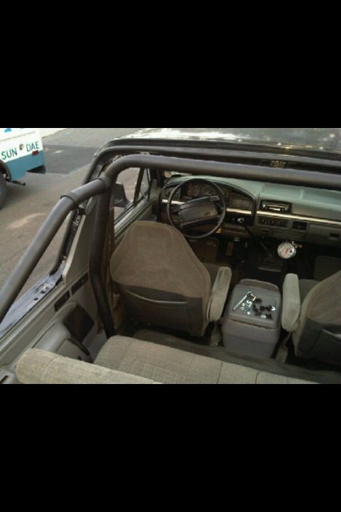 1995 Ford Bronco - The interior of a 1995 Ford Bronco is visible, its dashboard, seats, and a prominent roll cage.