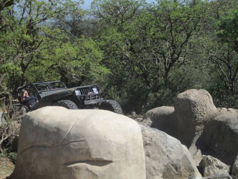1989 Ford Bronco - A Jeep Wrangler navigates a challenging off-road course, climbing over large rocks.