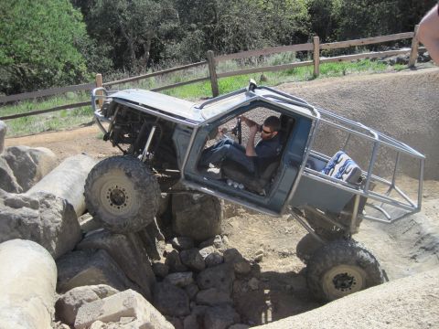 1989 Ford Bronco - Custom buggy with roll cage climbs over large rocks on an off-road trail.