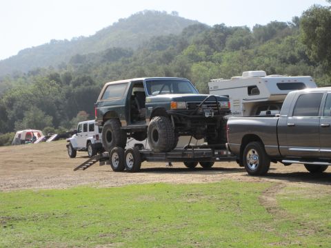 1989 Ford Bronco - A heavily modified green 1989 Ford Bronco is loaded onto a trailer, ready for transport.