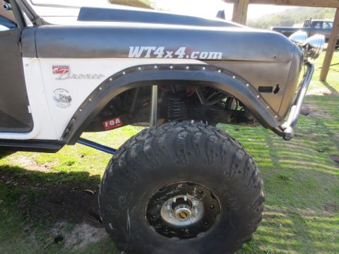 1989 Ford Bronco - A heavily modified Ford Bronco sits on large off-road tires, displaying a WT4x4.com decal on its fender.