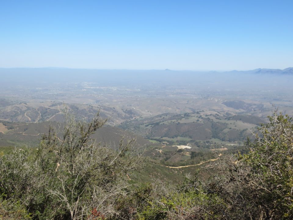 View from a hilltop overlooking a hazy valley with distant mountains