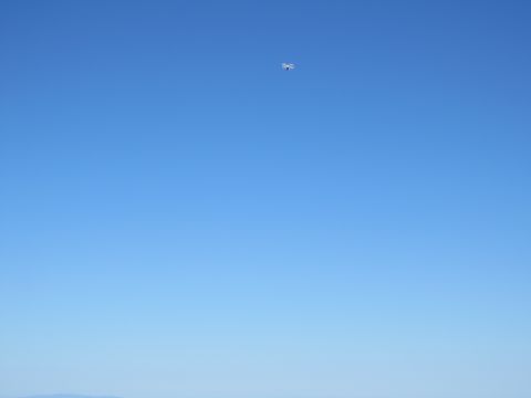 1989 Ford Bronco - A drone is visible against a vast expanse of clear blue sky.