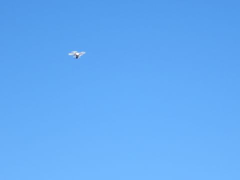 1989 Ford Bronco - A drone is captured in flight against a vast expanse of clear blue sky.