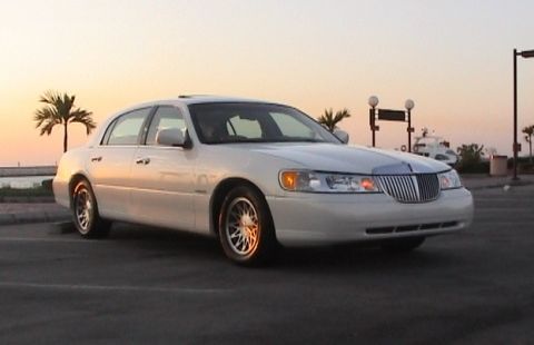 2002 Lincoln Town Car - A white 2002 Lincoln Town Car is seen from a three-quarter front view during a sunset, with palm trees in the background.