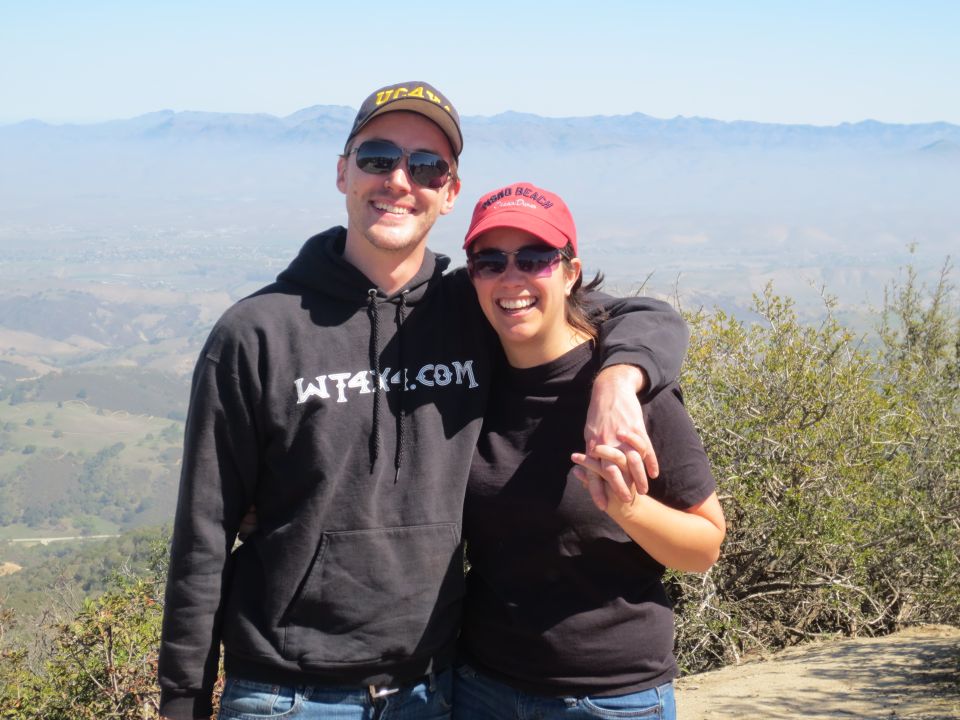 Guy wearing a WT4X4.COM hoodie and a girl in a red hat holding hands on a hill