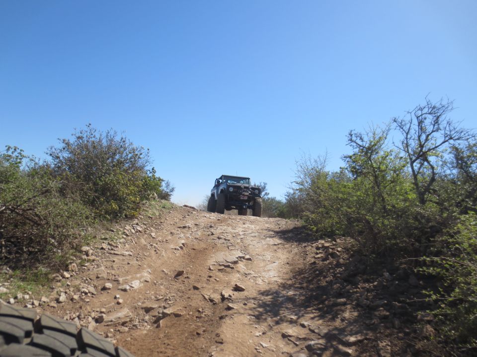 Jeep Wrangler driving up a rocky trail on a sunny day