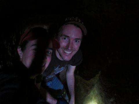 1989 Ford Bronco - Two individuals explore a dimly lit cave, illuminated by a light source.