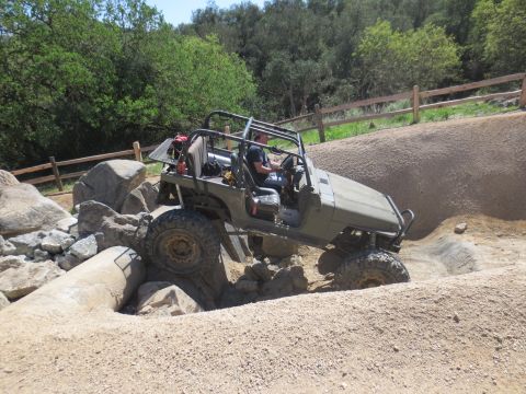 1989 Ford Bronco - An off-road vehicle maneuvers through a challenging rocky terrain on a sunny day.
