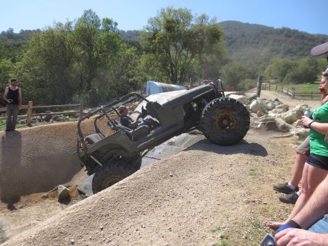 1989 Ford Bronco - An off-road buggy navigates a challenging dirt course with spectators watching.