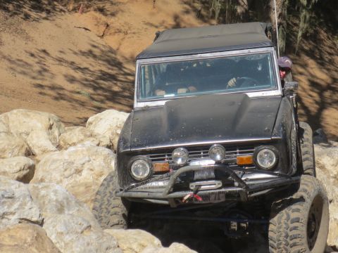 1989 Ford Bronco - A driver maneuvers a classic Ford Bronco over a challenging rocky terrain.