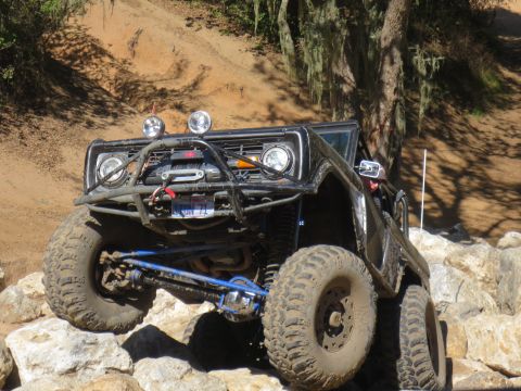 1989 Ford Bronco - This modified SUV navigates a rocky trail, its front end angled towards the viewer.