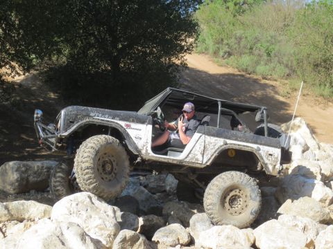 1989 Ford Bronco - This modified off-road vehicle navigates a rocky trail with a driver behind the wheel.