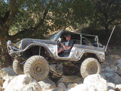 1989 Ford Bronco - This modified Bronco is navigating a rocky trail with a driver behind the wheel.
