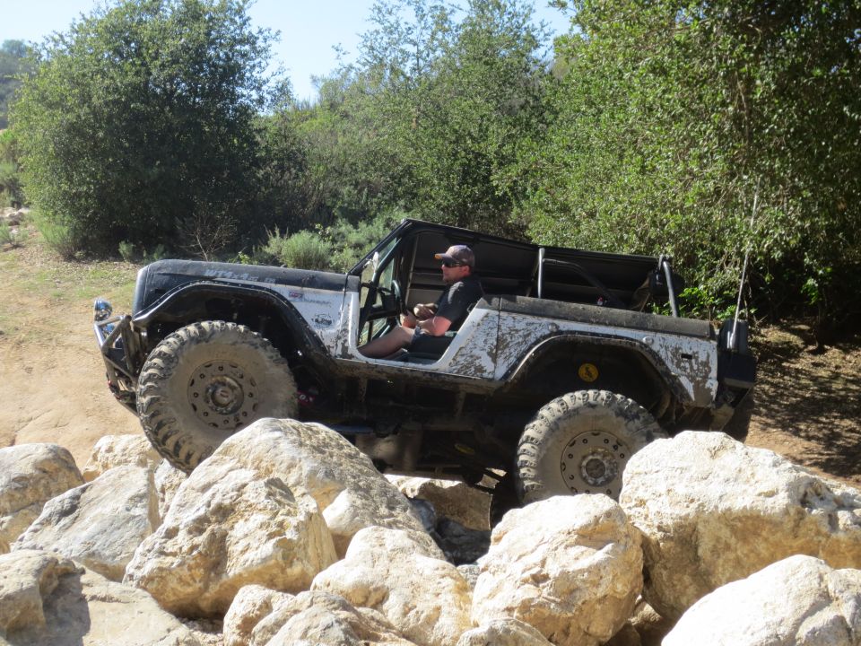 Off-road vehicle with large tires navigating a rocky trail