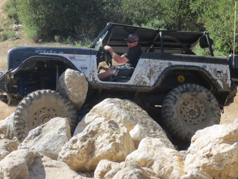 1989 Ford Bronco - This modified Ford Bronco is tackling a challenging rocky terrain, with its driver navigating carefully.