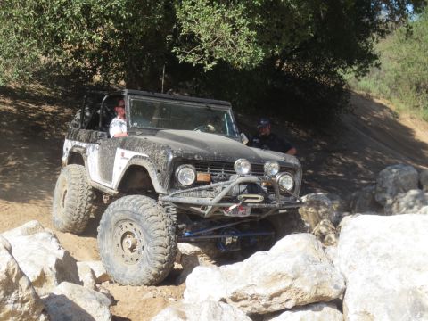 1989 Ford Bronco - This modified Ford Bronco is traversing a rocky trail, its front end angled towards the viewer.