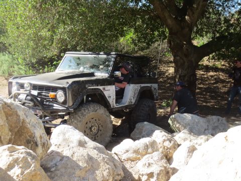 1989 Ford Bronco - A Ford Bronco navigates a rocky trail with a driver behind the wheel.