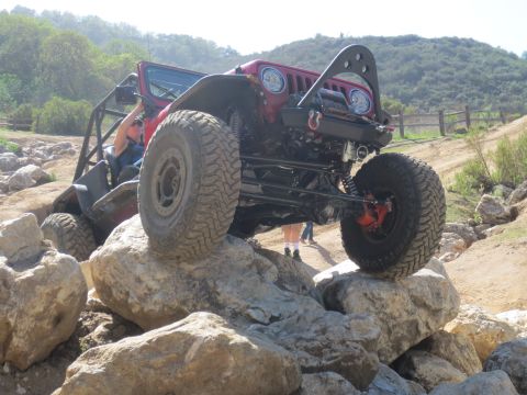 1989 Ford Bronco - This heavily modified Jeep is shown tackling a challenging rocky terrain on an off-road trail.