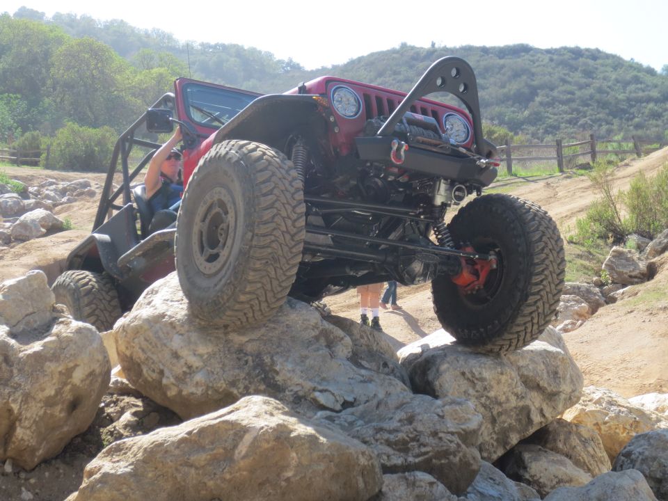 Red off-road Jeep navigating large rocks on a trail