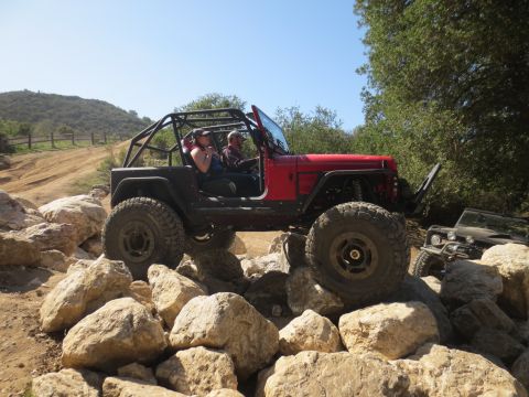 1989 Ford Bronco - Two off-road vehicles navigate a rocky trail under a clear blue sky.