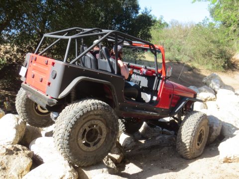 1989 Ford Bronco - This red off-road vehicle is equipped with a roll cage and large tires for tackling rocky terrain.