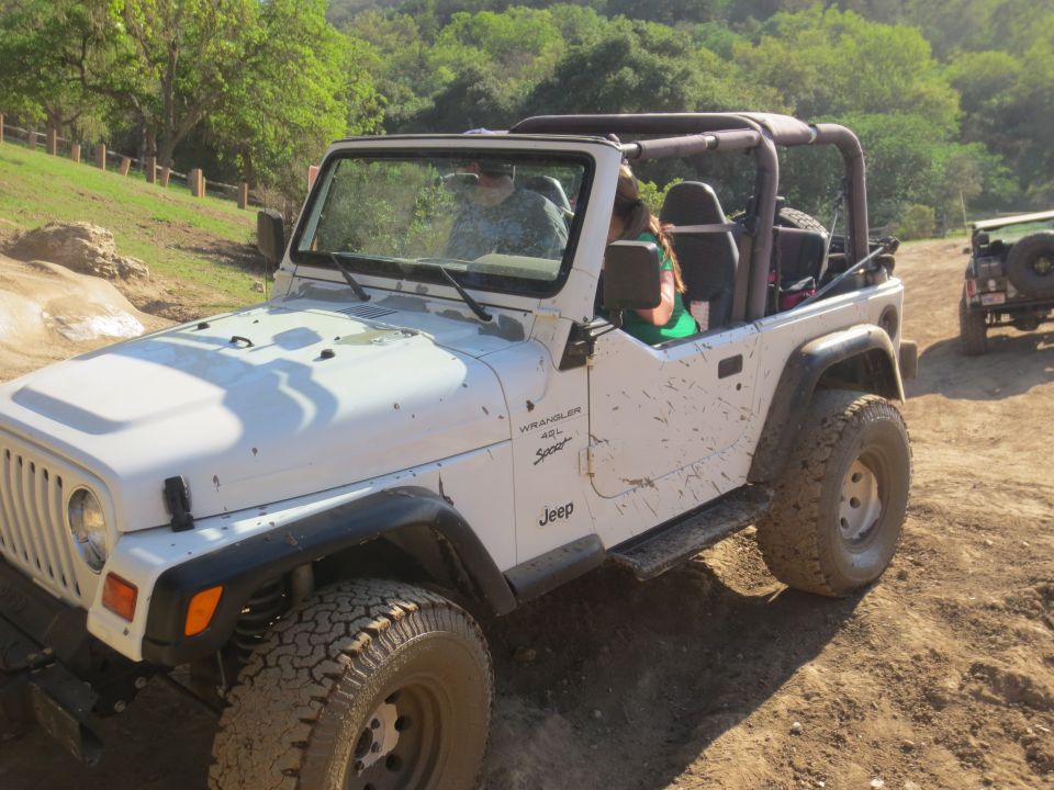 White Jeep Wrangler driving on a dirt trail with another Jeep behind it