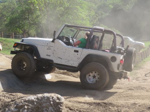 1989 Ford Bronco - A white Jeep Wrangler navigates a dirt trail, with another vehicle visible in the background.