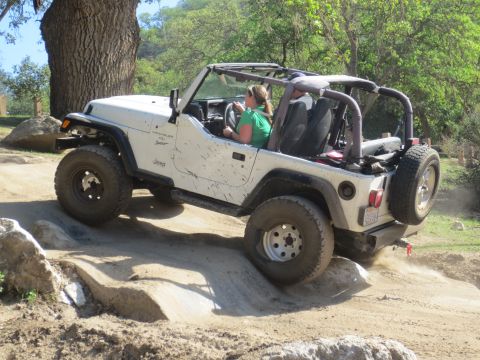 1989 Ford Bronco - A white Jeep Wrangler TJ navigates a challenging off-road course with a driver and passenger inside.