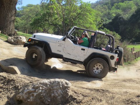 1989 Ford Bronco - A white Jeep Wrangler TJ navigates a rocky off-road course on a sunny day.