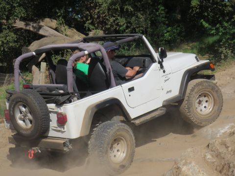 1989 Ford Bronco - A white Jeep Wrangler navigates a rocky, dusty off-road trail with two occupants.