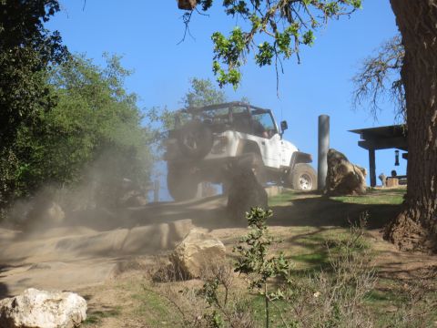 1989 Ford Bronco - A white Jeep Wrangler navigates a dusty off-road trail.