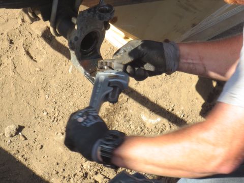 1989 Ford Bronco - A person works on a vehicle's suspension system, using a tool to adjust a part.