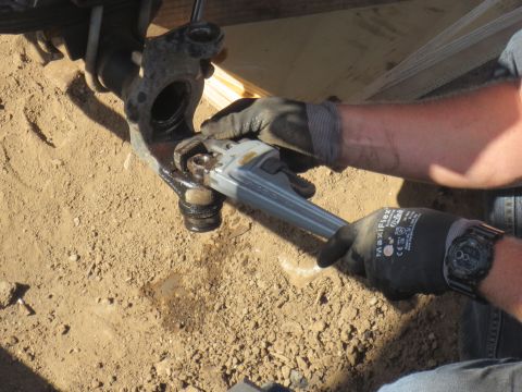 1989 Ford Bronco - A mechanic tightens a suspension component with a pipe wrench.