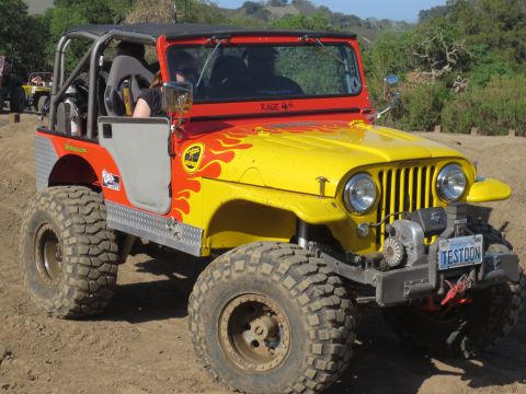1989 Ford Bronco - This modified jeep features a flame paint job and off-road tires, with another vehicle visible in the background.