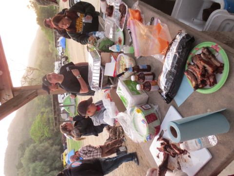 1989 Ford Bronco - A group of people enjoy a picnic with a spread of ribs, salads, and barbecue sauces on a table.