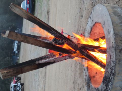 1989 Ford Bronco - Logs burning in a concrete fire pit with vehicles in the background.