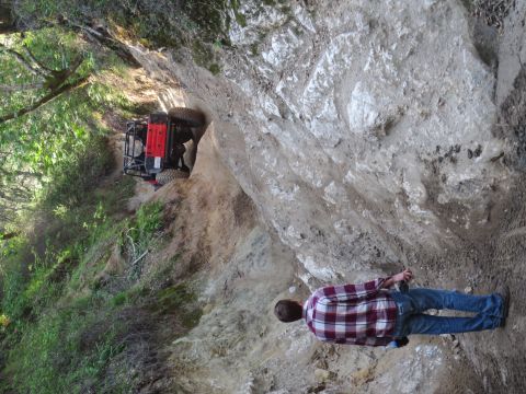 1989 Ford Bronco - An off-road vehicle carefully maneuvers along a steep, dirt path surrounded by trees and rocks.