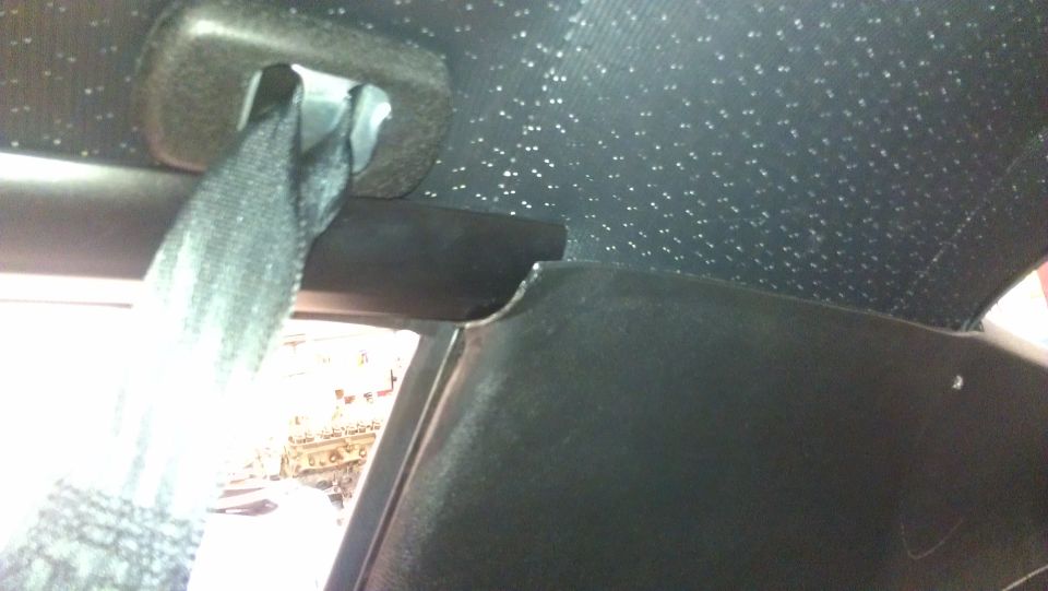 Black car interior with a seatbelt and a speckled headliner