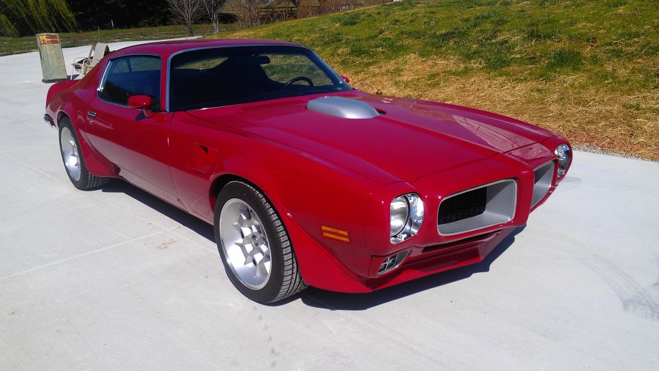 Red Pontiac Firebird with silver shaker hood scoop and aftermarket wheels