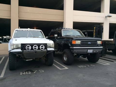 1968 Ford Mustang - Two modified trucks, a white off-road vehicle and a black Ford Bronco, are parked in a garage.