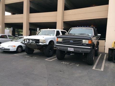 1968 Ford Mustang - Two lifted Ford trucks are parked side-by-side in a parking garage.