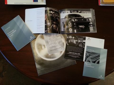 2003 Mercury Marauder - Promotional materials for the 2003 Mercury Marauder, including a brochure and maintenance guide, are laid out on a table.