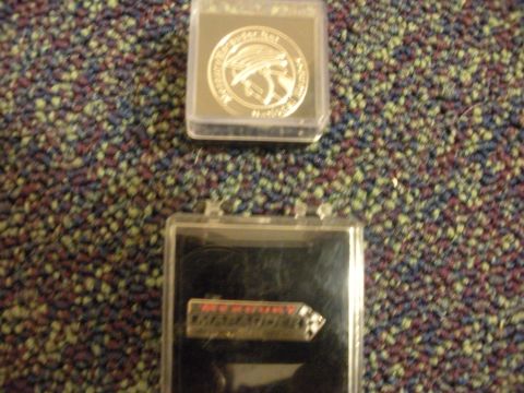 2003 Mercury Marauder - Mercury Marauder lapel pin and coin are displayed in plastic cases on a carpeted surface.