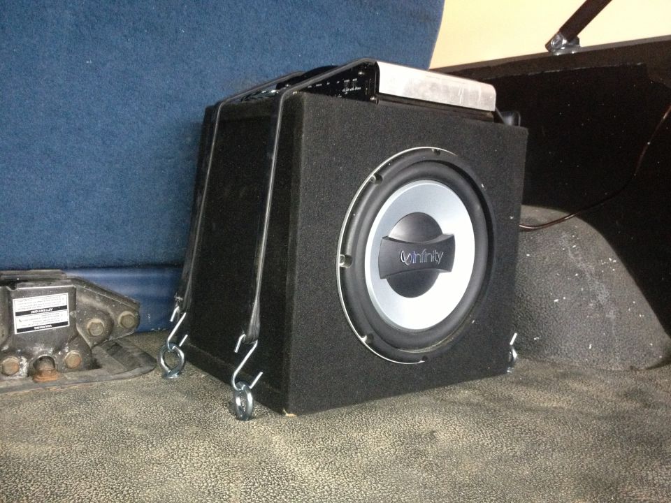 Infinity subwoofer mounted in vehicle interior with straps